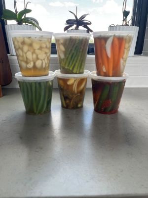 Six containers of Burque Brine pickles on a kitchen counter