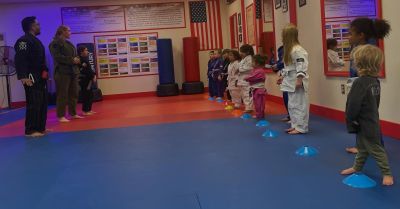 Instructors leading a kids Brazilian Jiu-Jitsu class on the mats